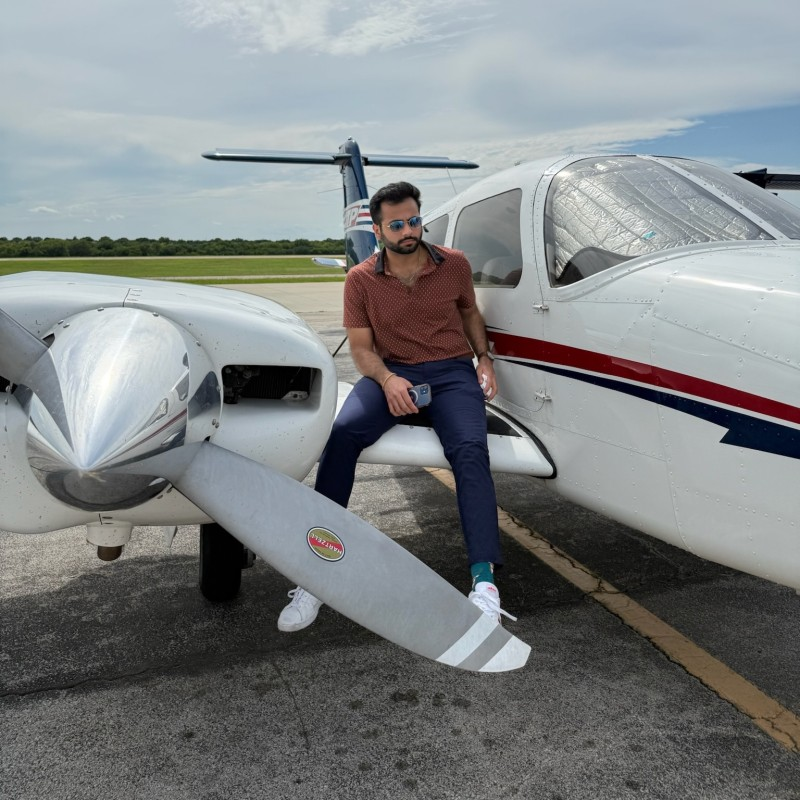 Tan Gangani sitting beside a light aircraft on the tarmac